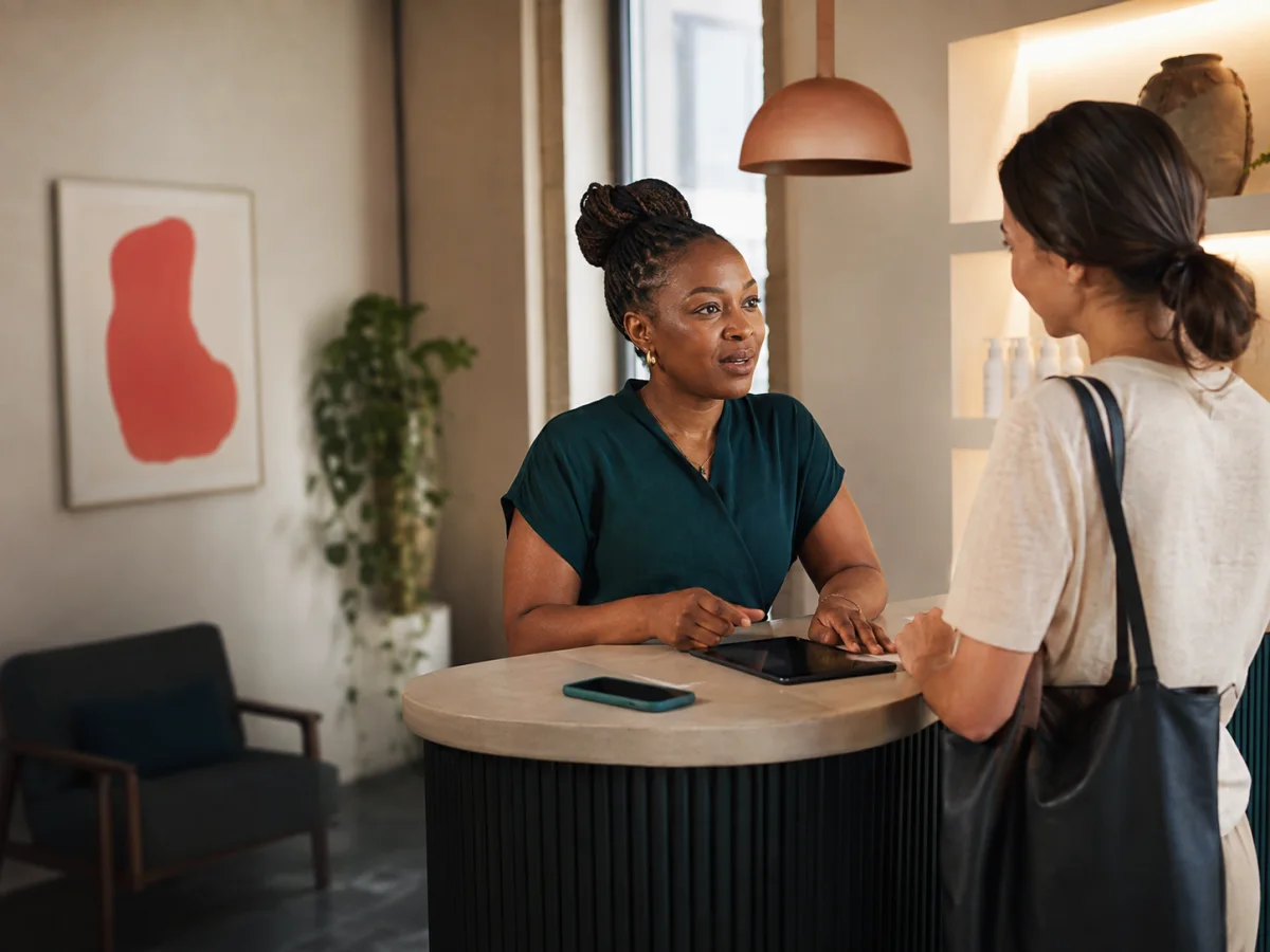 Wellness clinic owner helping a client while a message waits on her phone